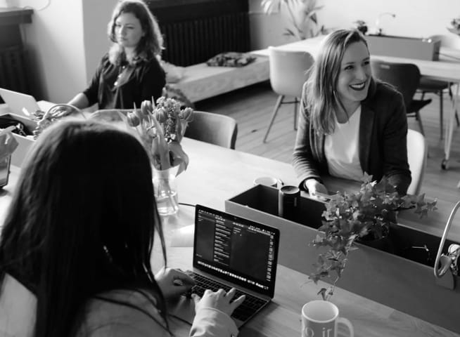 Black and white picture of ladies working on their PCs and chatting